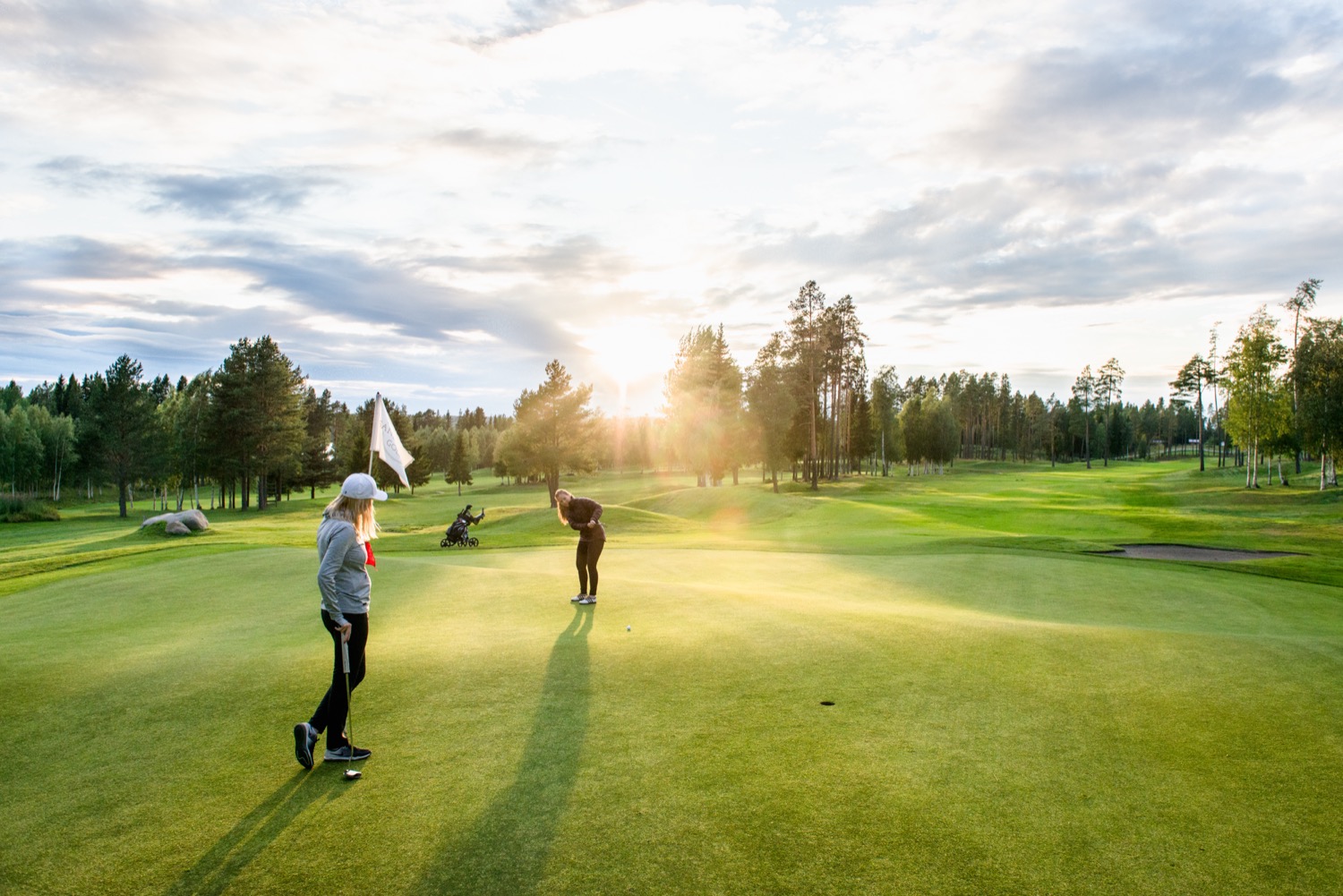 Två spelare på green i kvällsljus